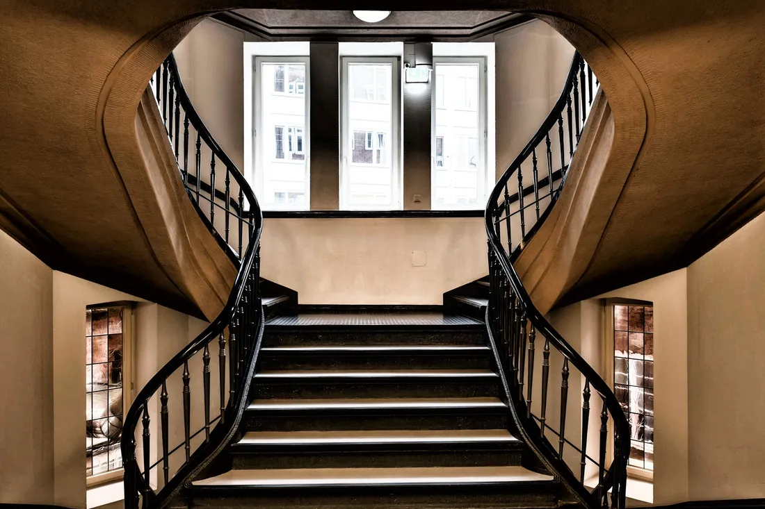 Elegantes Berliner Altbau-Treppenhaus mit geschwungenem Geländer und hohen Decken